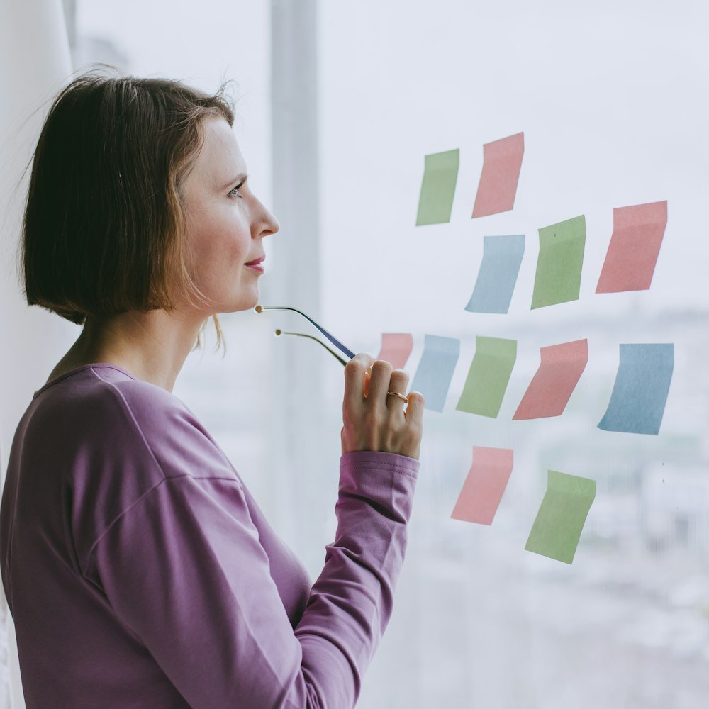 Persona planificando con notas adhesivas junto a la ventana